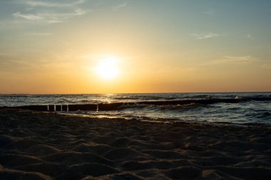Aşağıdan, Groyne 'daki kumlu sahilden, gün batımında dalgalar ve deniz manzarası