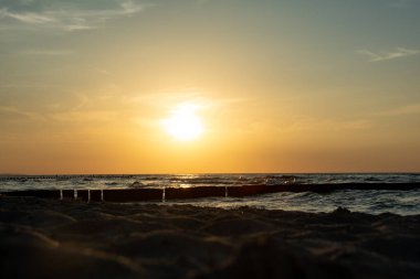 Aşağıdan, Groyne 'daki kumlu sahilden, gün batımında dalgalar ve deniz manzarası