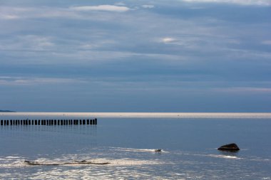 Durgun denizde, Baltık Denizi kıyısında, mavi gökyüzü olan ahşap damızlıklar.