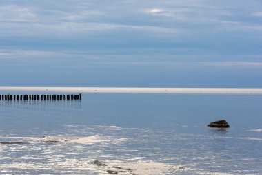 Durgun denizde, Baltık Denizi kıyısında, mavi gökyüzü olan ahşap damızlıklar.