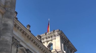 Almanya bayrağı Reichstag binasının çatısında. Kumaş bayrakları rüzgarda dalgalanıyor.