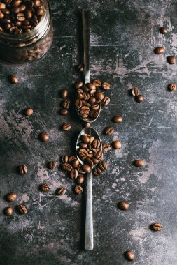 Kahveyle dolu bir kavanozun yanında Black Beton desenli bir arka plan üzerine iki kaşık dolusu kahve tozu. Kahve konsepti