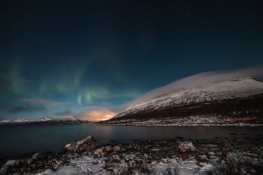 Borealis aurora sweeps over a large lake on a cloudless night in Kilpisjarvi, Lapland, Finland. aurora polaris in green dances across the sky. Scandinavian magic. Saana mountain in fog. clipart