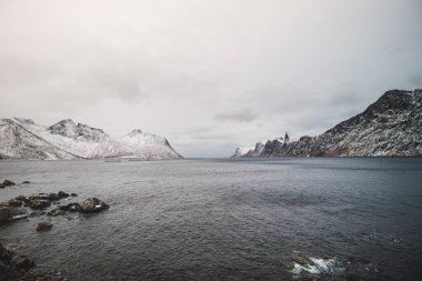 Norveç 'in Senja adasındaki ıssız Husoy köyünden görüntü. Çok yalnız bir balıkçı köyü. Fırtınalı Norveç denizi ve Kuzey Kutbu 'nun ötesindeki karlı tepelerin manzarası.