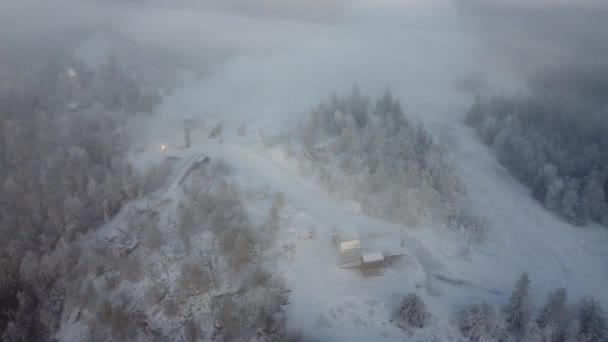フィンランドのカイヌー州ブカティインバラの丘の上の飛行のドローン映像 日の出に濃霧の中に隠れて 上から雪に覆われたフィンランドの風景の眺め 4Kビデオ — ストック動画