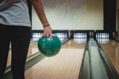 Bowling kızı, özel olarak modifiye edilmiş bir bovling salonunda atacağı atağa hazırlanıyor. Boş zaman geçirmek. Bir kadın yeşil bir top tutuyor ve turuna başlıyor. Sotkamo, Finlandiya.