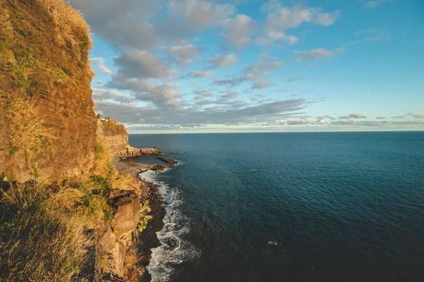 Portekiz 'in Madeira adasının açıklarında Atlantik kıyısında gün batımı. Ponta do Sol 'da altın ışıkla aydınlatılmış devasa kayalar. Madeira keşfediliyor. 
