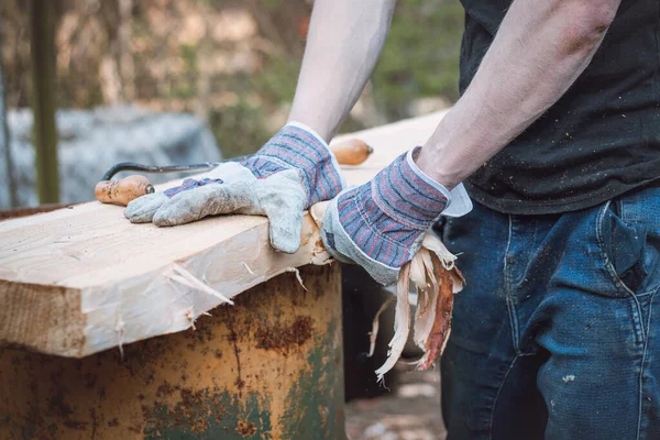 Kullanışlı oduncu tarla kuşunu sonraki işlem için hazırlıyor. Planlama tahtası. Tarla kuşlarını geleneksel aletlerle çalıştırmak. El işleme. Ağaç gövdesini buduyorum. Çalışan kasların ayrıntıları.