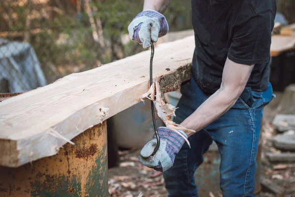 Kullanışlı oduncu tarla kuşunu sonraki işlem için hazırlıyor. Planlama tahtası. Tarla kuşlarını geleneksel aletlerle çalıştırmak. El işleme. Ağaç gövdesini buduyorum. Çalışan kasların ayrıntıları.