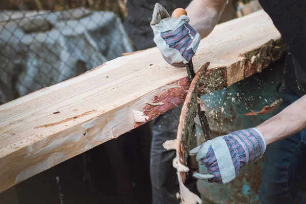 Genç oduncu tarla kuşunu sonraki işlem için hazırlıyor. Planlama tahtası. Tarla kuşlarını geleneksel aletlerle çalıştırmak. El işleme. Ağaç gövdesini buduyorum..