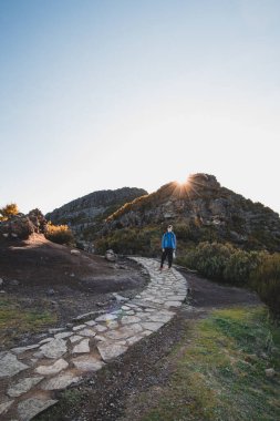 Madeiras 'ın en yüksek dağı Pico Ruivo' da bulunan Encumeada Baixa dağının altında yürüyüş rotası. Güneş Madeiran dağlarının yamacında parlıyor. Portekiz adasını keşfedin.