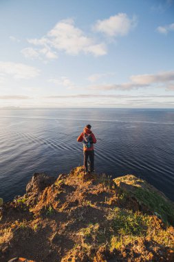 24 yaşındaki tutkulu gezgin, Portekiz 'e ait Cristo Rei, Camara de Lomos, Madeira adlı bir yerdeki uçurumun kenarında duruyor. Atlantik kıyısında gün doğumu.