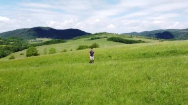 Kahverengi saçlı voleybol oyuncusu güneşli bir günde bir tepenin tepesinde ısınma antrenmanından önce ortalığı sallıyor. Genç bir sporcunun sağlıklı ve aktif yaşam tarzı. 4k video