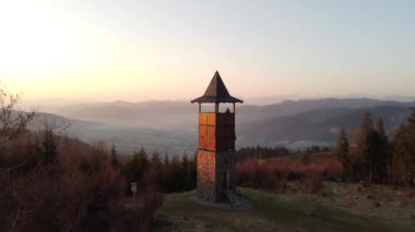 Zborov nad Bystrica kasabası yakınlarındaki Slovak kırsalında gün doğumu manzaralı. Oravsk Magura vadisindeki taş kule. Sabah turuncu yumuşak ışık. İHA atışı