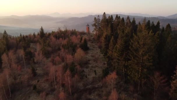 Východ slunce nad slovenskou krajinou s výhledem na Zborov nad Bystricí. Kamenná věž v údolí Oravské magury. Ranní oranžové měkké světlo. Výstřel dronů