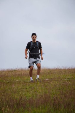 Esmer tipli bir adam çakıllı tepeden aşağı koşuyor, yaralanmamak için attığı her adımı kontrol ediyor. Etkin atlet fitness, koordinasyon ve hareketin hassasiyetini geliştirmek için zorlu arazide koşuyor.