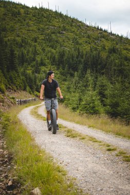 Esmer tipli bir insan, Jeseniky Dağları 'ndaki dik bir orman yolunda yokuş aşağı bir dağ scooter' ına biner. Dolni Morava tatil köyü. 