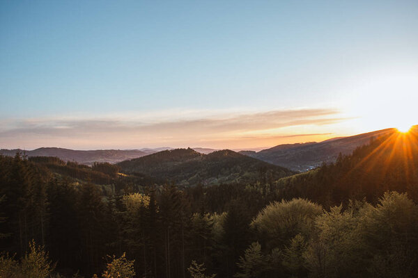 Sunset over the Moravian-Silesian part of the Czech Republic in Beskydy mountains. Orange glow of the sun in the early evening over a mixed forest. Wilderness.