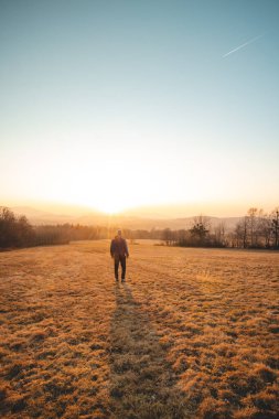 Young ambitious tourist walks through the grain fields at sunset in the Beskydy Mountains, Czech Republic. Reflecting on himself. A walk in the fresh air.