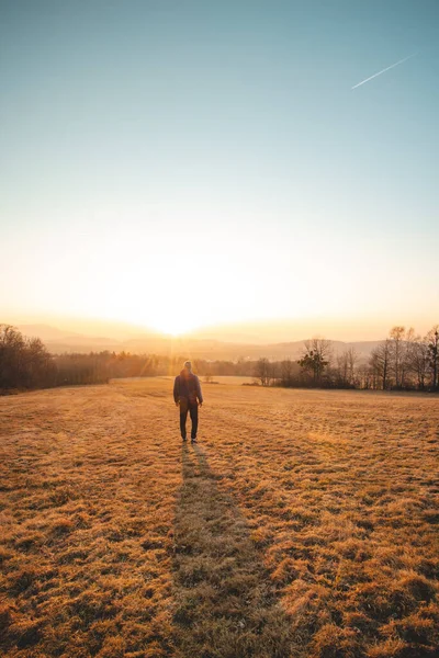 Young ambitious tourist walks through the grain fields at sunset in the Beskydy Mountains, Czech Republic. Reflecting on himself. A walk in the fresh air.