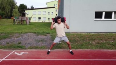 Goal-oriented athlete does lunges with a water booster bag on his back for greater load on the lower limbs. Workout on the workout court.  Aquahit on an athlete. 