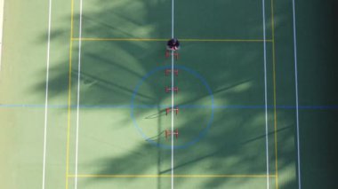 Blond athlete in a blue T-shirt develops his dynamic strength by jumping over hurdles on an athletic oval. 4k video