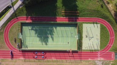 Aerial view on two athletes trotting along a challenging course on the athletics oval. Running to calm down and lower the heart rate. Conditioning exercise.