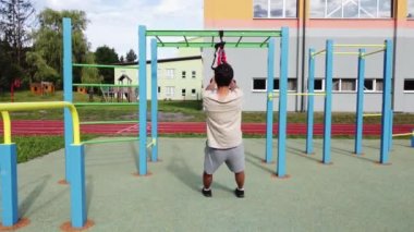 active, enthusiastic athlete performs exercises for a stronger midsection and stretching of the respective limbs on Trx fitness straps. Train upper body chest shoulders pecs triceps.