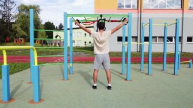 active, enthusiastic athlete performs exercises for a stronger midsection and stretching of the respective limbs on Trx fitness straps. Train upper body chest shoulders pecs triceps.