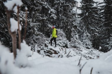 Beskydy Dağları 'nın karlı manzarasını keşfeden hevesli bir yürüyüşçünün portresi. Karla kaplı bir kayanın üstünde duran bir turist.