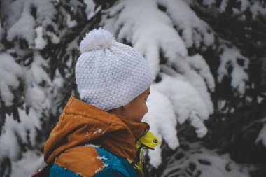 Kış mevsiminde karlı bir bölgede kış rengi ceket ve beyaz şapka giyen genç bir adamın samimi portresi. Yeni alanlar keşfediliyor.