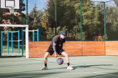 Genç yetenek antrenmanlarında ayaklarının altına basketbol topu sürüyor ve el, vücut ve ayak koordinasyonunu geliştiriyor. Basketbol maçı. Numarayı, aldatmacayı öğrenmek..