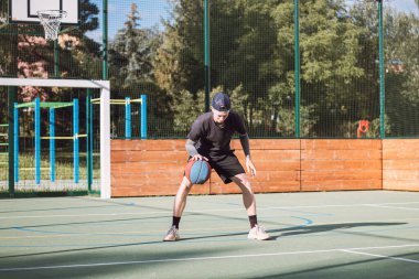 Genç yetenek antrenmanlarında ayaklarının altına basketbol topu sürüyor ve el, vücut ve ayak koordinasyonunu geliştiriyor. Basketbol maçı. Numarayı, aldatmacayı öğrenmek..