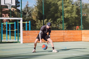Genç yetenek antrenmanlarında ayaklarının altına basketbol topu sürüyor ve el, vücut ve ayak koordinasyonunu geliştiriyor. Basketbol maçı. Numarayı, aldatmacayı öğrenmek..