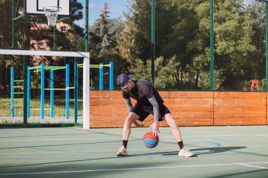 Genç yetenek antrenmanlarında ayaklarının altına basketbol topu sürüyor ve el, vücut ve ayak koordinasyonunu geliştiriyor. Basketbol maçı. Numarayı, aldatmacayı öğrenmek..