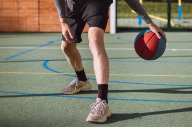 Genç yetenek antrenmanlarında ayaklarının altına basketbol topu sürüyor ve el, vücut ve ayak koordinasyonunu geliştiriyor. Basketbol maçı. Numarayı, aldatmacayı öğrenmek..