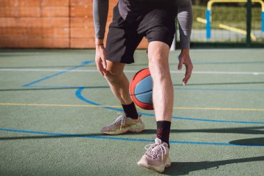 Genç yetenek antrenmanlarında ayaklarının altına basketbol topu sürüyor ve el, vücut ve ayak koordinasyonunu geliştiriyor. Basketbol maçı. Numarayı, aldatmacayı öğrenmek..