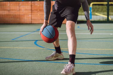 Genç yetenek antrenmanlarında ayaklarının altına basketbol topu sürüyor ve el, vücut ve ayak koordinasyonunu geliştiriyor. Basketbol maçı. Numarayı, aldatmacayı öğrenmek..