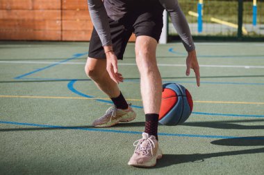 Genç yetenek antrenmanlarında ayaklarının altına basketbol topu sürüyor ve el, vücut ve ayak koordinasyonunu geliştiriyor. Basketbol maçı. Numarayı, aldatmacayı öğrenmek..