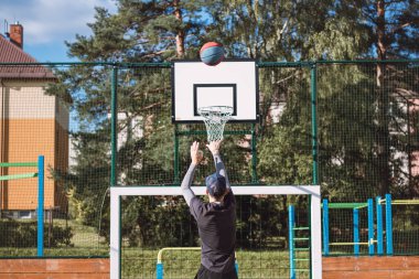 Spor giyim antrenmanındaki sarışın çocuk üç sayılık çizginin arkasından basket atıyor. Açık hava basketbol sahası. Mevsime hazırlanıyorum..