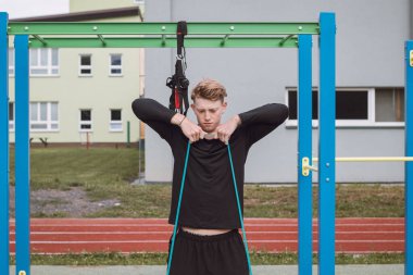 Spor eğitmeni, vücudun üst kısmını sabah spor salonunda genişleticilerin ve lastik bantların yardımıyla çalıştırır. Trapezius, omuz kasları çalışıyor..