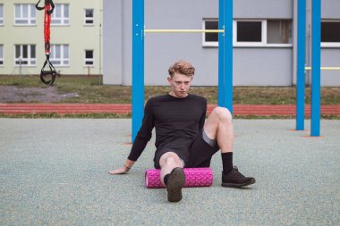 Spor eğitmeni kas gruplarına etkin bir şekilde etki eden masaj rulosunun yardımıyla vücudun alt kısmını çalıştırır ve ısıtır. Femoris kaslarını ısıtıyorum..