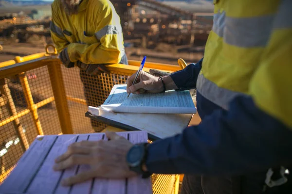 Safety workplace miner supervisor reviewing and sign of approval working at heights permit document prior to performing high risk work on construction plant mine site, Perth, Australia 