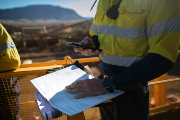 Safety workplace miner supervisor checking site emergency phone number before sigh of confined space permit prior to performing high risk work on construction mine site, Perth, Australia 