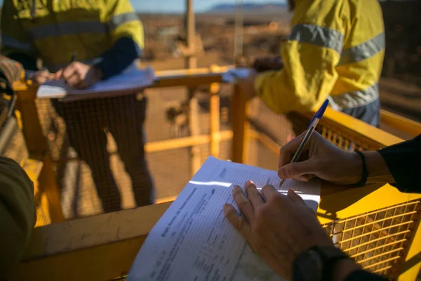Rope access miner supervisor sign of JSA risk assessment permit to work on site prior to performing high risk work on construction mine site, Perth, Australia 