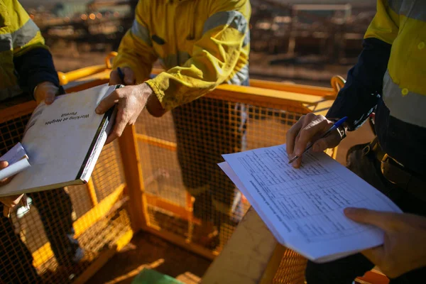 Safety first at work place miner supervisor checking reviewing document before issued sigh of working at height permit JSA risk assessment on site prior to performing high risk work on construction mine site, Perth, Australia