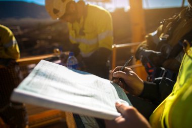 Safety workplace group of construction miner workers signing off working at heights permit on open field job site prior to starting high risk work of each shift construction mine site Australia