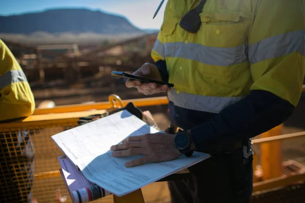 Miner supervisor checking site emergency phone number before sigh of confined space permit prior to performing high risk work on construction mine site, Perth, Australia