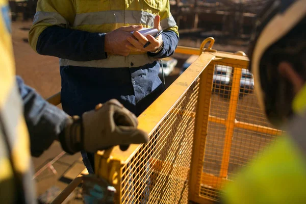 Safety workplace group of miner workers looking at personnel risk assessment take five book before written risk assessment prior to work of each task at construction mine site Perth, Australia