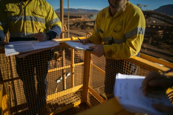 Safety workplace rope access miner supervisor sign of JSA risk assessment permit to work on site prior to performing high risk working at heights on construction mine site, Perth, Australia